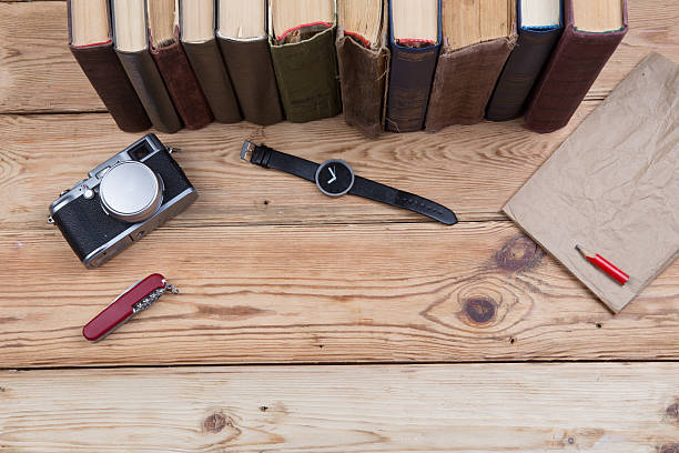 istock Top view on wooden desktop with books, watch and camera 579420812