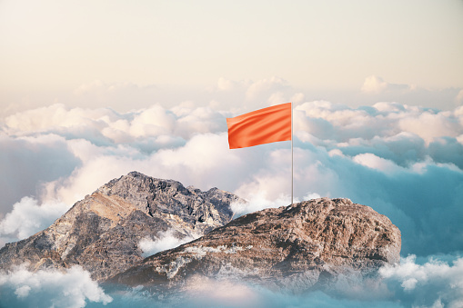 Leadership and success concept with blank red flag on mountain top. Mock up