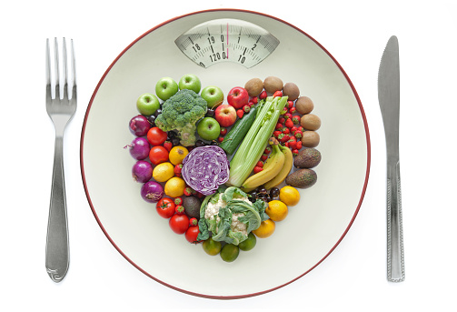Plate with weighing scales packed with fruits and vegtables in a heart shape