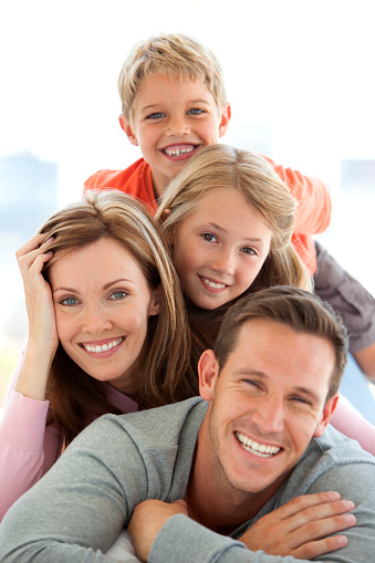 Portrait of a Happy Caucasian family with two children lying down on bed and making a human pyramid
