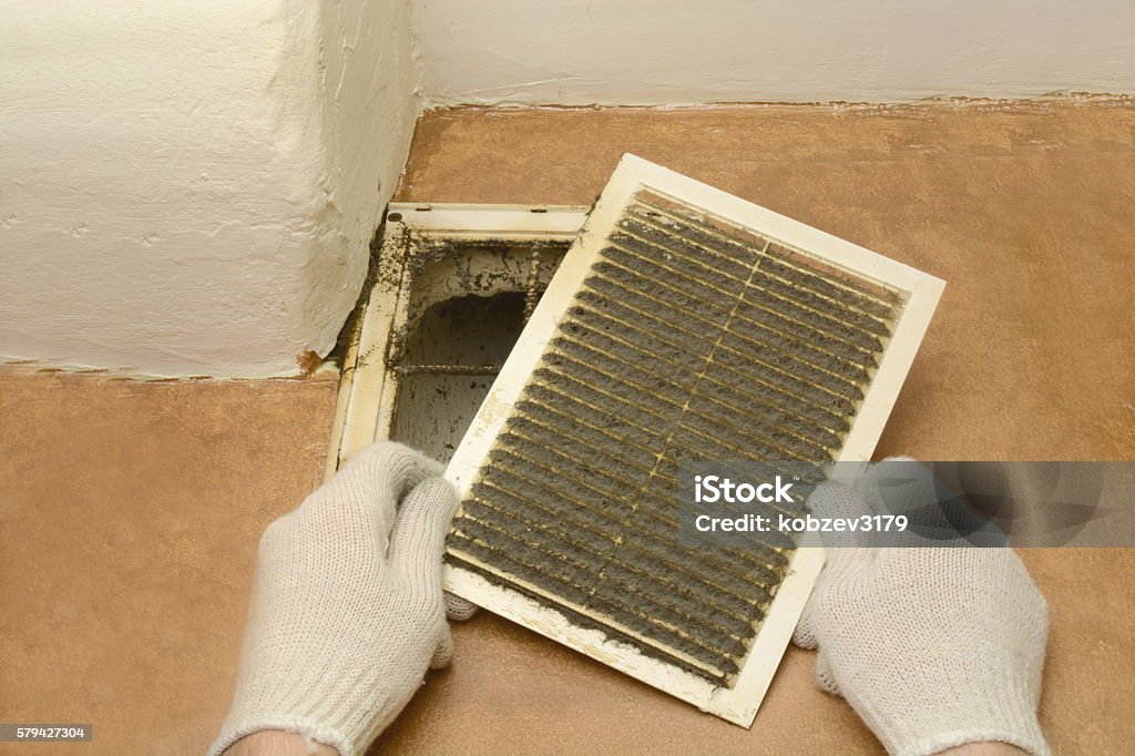 man removes dust ventilation grilles Man removes dust ventilation grilles in white gloves Air Duct Stock Photo