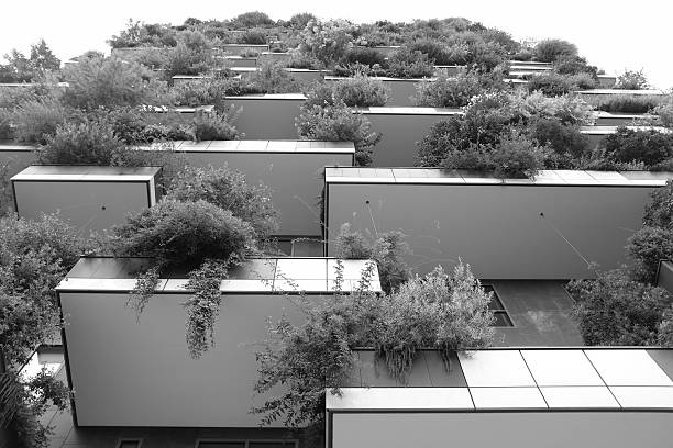A tall, grey apartment building is seen from a low angle. The building has many windows and balconies. There are no people visible.
