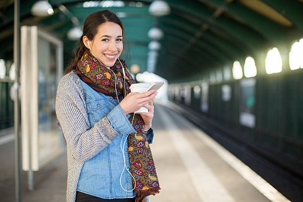 улыбающаяся молодая женщина ждет на станции метро - rush hour audio стоковые фото и изображения