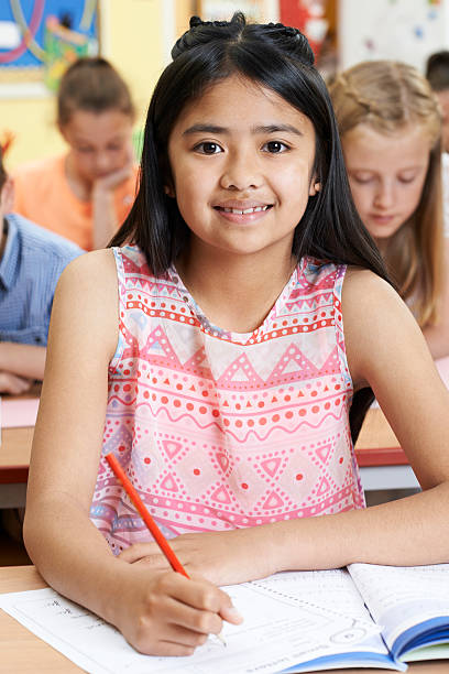 istock Female Elementary School Pupil Working At Desk 579430030