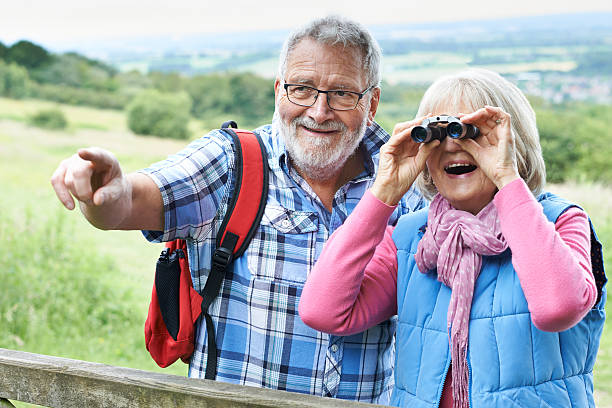 istock Senior Couple Hiking In Countryside Looking Through Binoculars 579430756