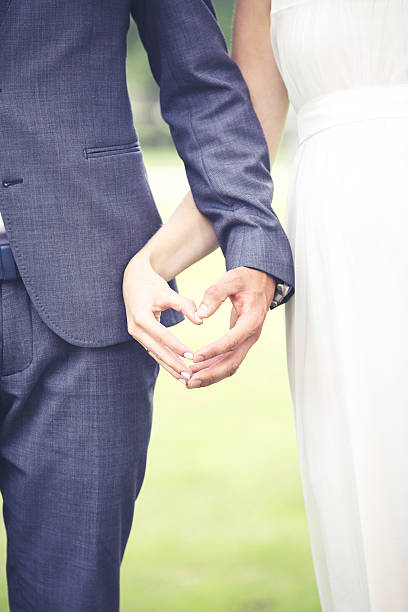 istock wedding - bride and fiance showing heart shape with hands 579431520