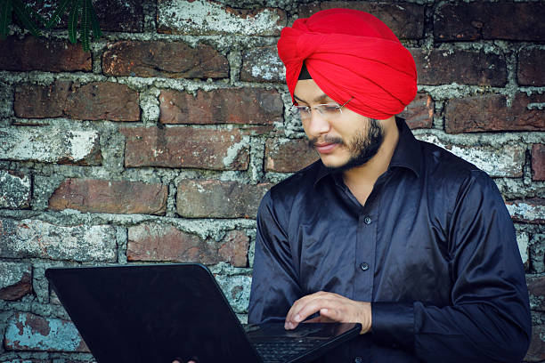 istock young Sikh man holding computer laptop working urban business 579434402
