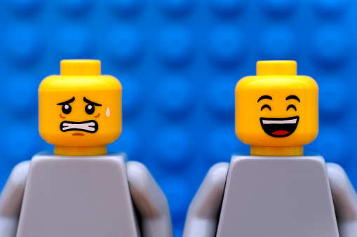 Tambov, Russian Federation - July 24, 2016: Two Lego minifigures - one scared and one happy. Blue background. Studio shot.