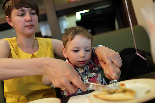istock Mother teaches her son to use cutlery 579435224