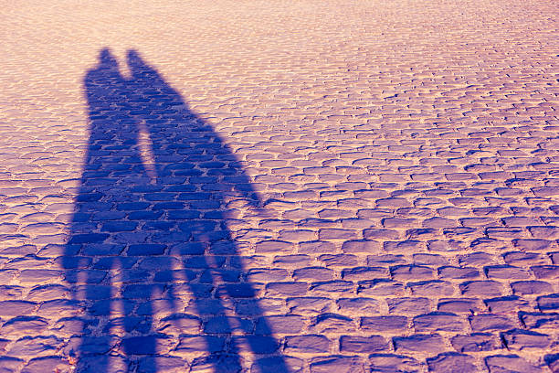istock Couple shadow on old stone pavement 579438788