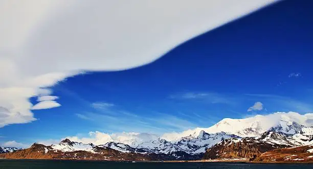 Lenticular clouds form on the edge of a cold front as it moves over the northern coast mountains of South Georgia.