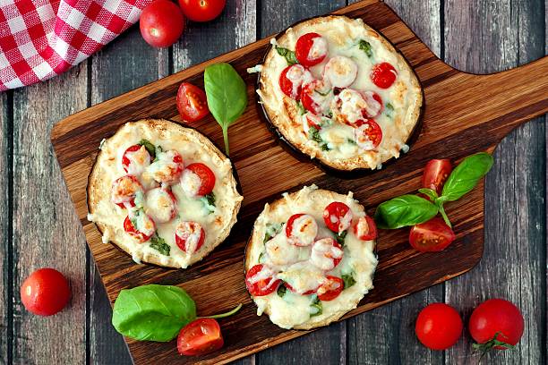 istock Eggplant mini pizzas on serving board against rustic wood 579443648