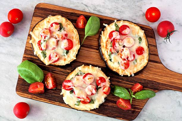 istock Eggplant mini pizzas on a serving board against marble 579443752