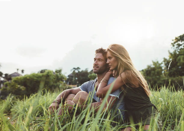 istock Young couple sitting together in meadow 579447084