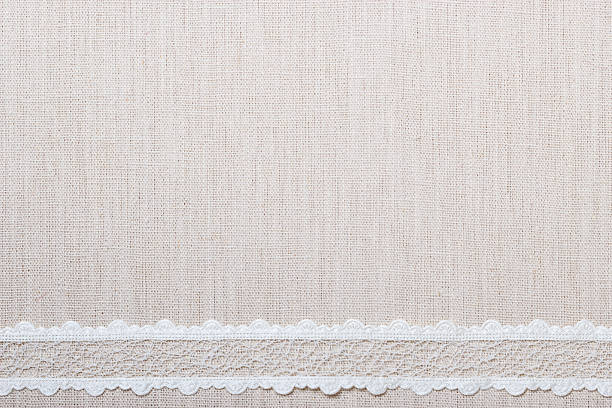 Lace ribbon on natural linen, bright cloth fabric background. Border frame