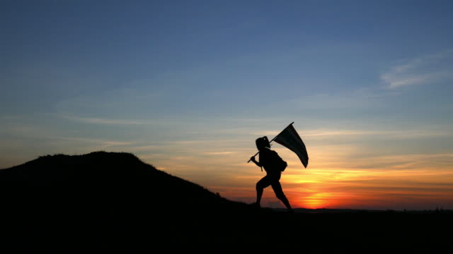 Silhouette of   young woman walking with a flag