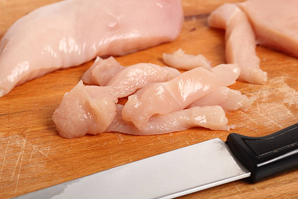 istock Cutting chicken breast into strips on wooden kitchen board 579731524