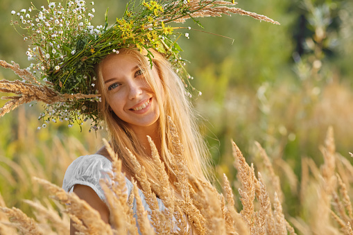 happy young woman in a crown from a grass