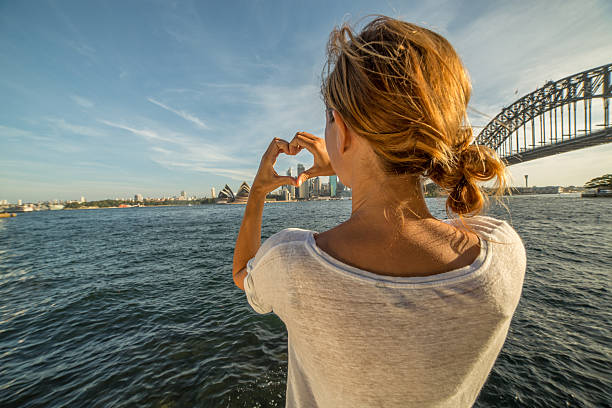 istock Young woman makes heart shape finger frame on Sydney skyline 579732778