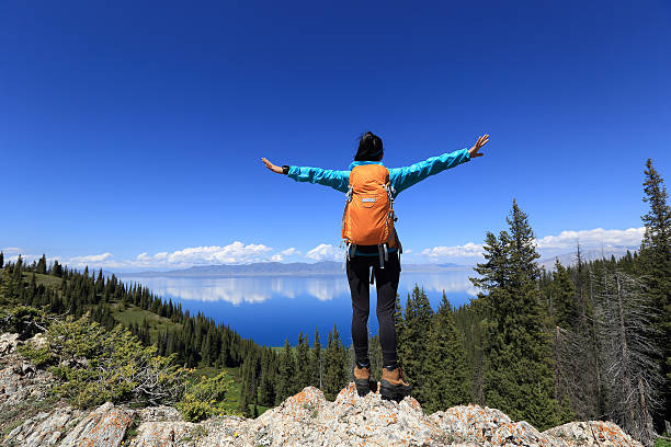 istock cheering successful woman backpacker open arms on mountain peak 579736034