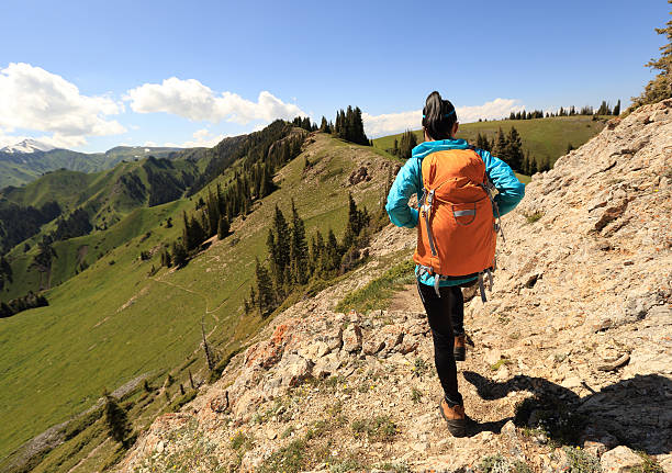 young woman backpacker hiking on mountain peak trail