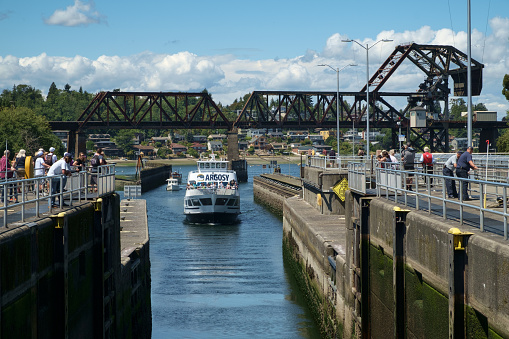 Seattle, USA July 20, 2016: Tour boat crowded with tourists enters Hiram Chittenden (Ballard) Locks. Tourist gather at locks to watch tour boat