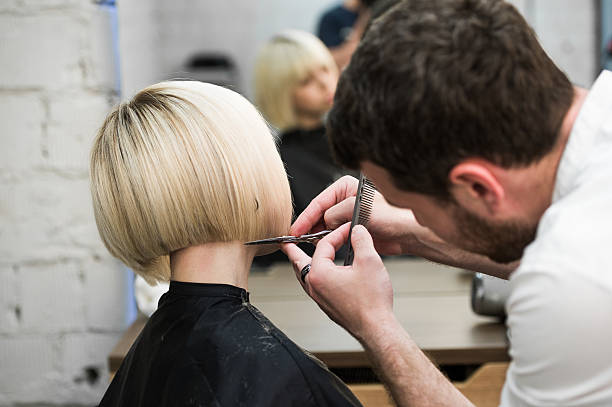 Hairdresser cutting client's hair in salon with electric razor Hairdresser cutting client's hair in salon with electric razor closeup cutting hair photos stock pictures, royalty-free photos & images