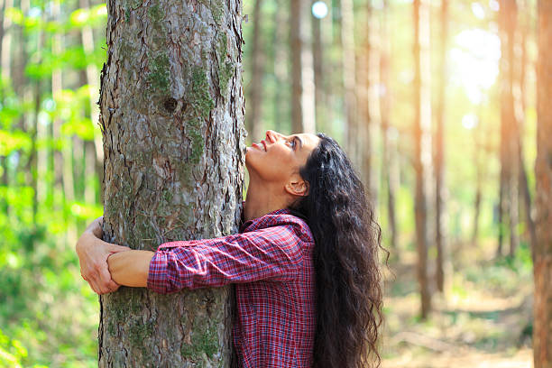 istock Young woman with long hair hugging tree in the forest 579746192