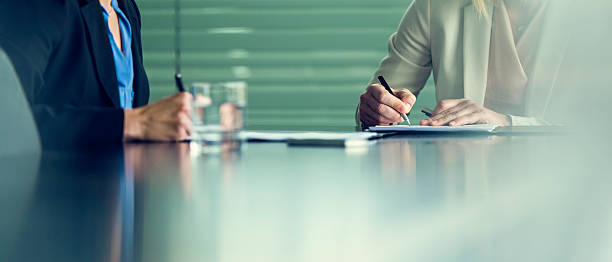 primo piano di due imprenditrici che firmano contratti a una conferenza - office water business meeting foto e immagini stock