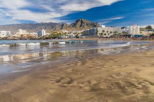 Tenerife, Spain - January 23, 2016: Crowd of people swimming and sunbathing on the picturesque Playa de Troya beach of Costa Adeje resort.
