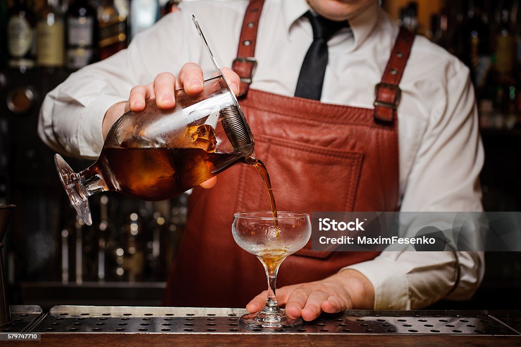 Bartender pouring fresh cocktail in fancy glass Bartender pouring fresh cocktail in fancy glass with ice Bartender Stock Photo