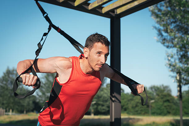 istock Man doing push ups training arms with trx fitness straps 579753964