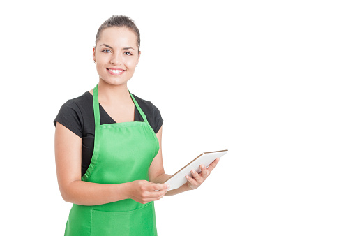 Successful hypermarket employee with green apron holding modern tablet isolated on white background with copyspace