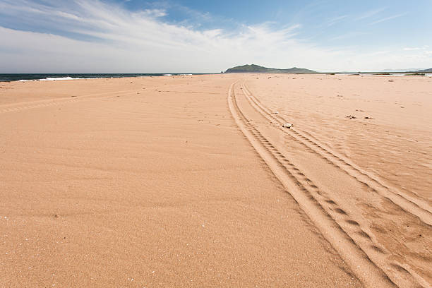 сцена длинного автомобильного следа на пляже в солнечный день. - pattern blue sea sand стоковые фото и изображения