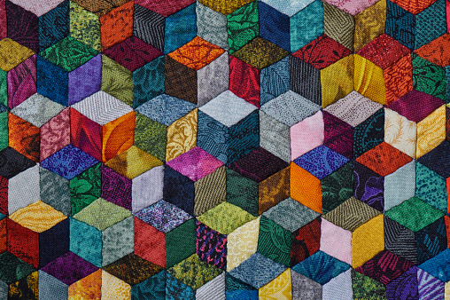 Colorful detail of quilt sewn from diamond pieces