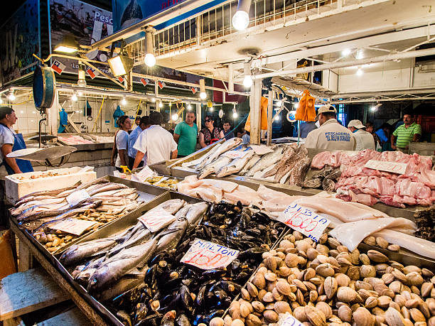 Santiago, Chile - February 20, 2013: Various kinds of fishes and other seafood for sale inside Mercado Central de Santiago in Santiago, Chile. Vendors can be seen preparing fishes for the customers.