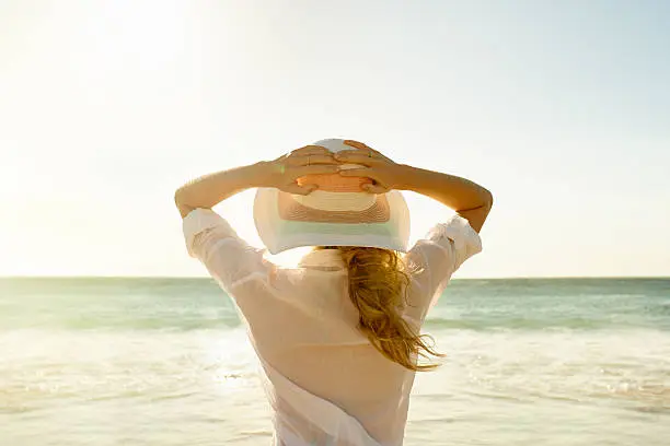 Rearview shot of a young woman standing on the beach