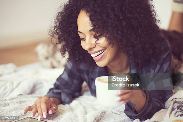 Afro American Woman Using A Digital Tablet At Home Stock Photo - Download Image Now - Winter, Cozy, Reading