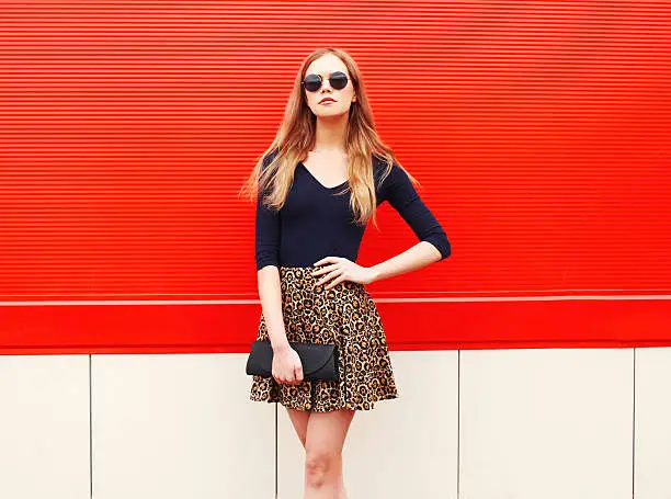 Photo of Fashion beautiful woman in leopard skirt sunglasses handbag clutch posing