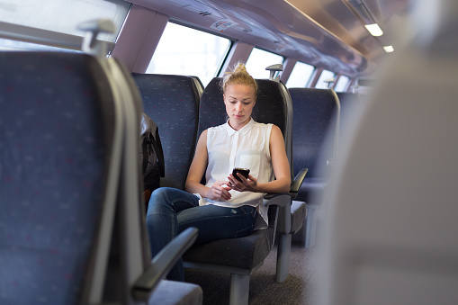 Woman workin on smart phone while traveling by train. Business travel concept.