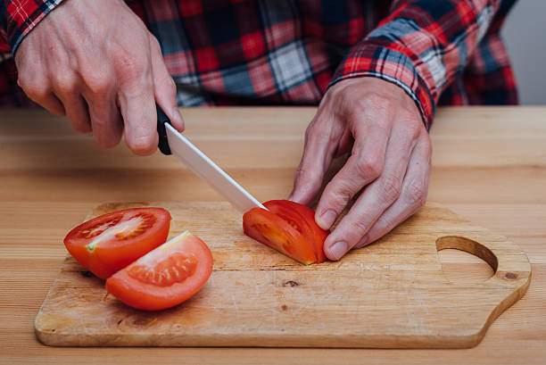 istock Man hands slicing fresh tomato by ceramic knife 579767842