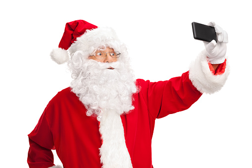 Studio shot of Santa Claus taking a selfie with a cell phone isolated on white background