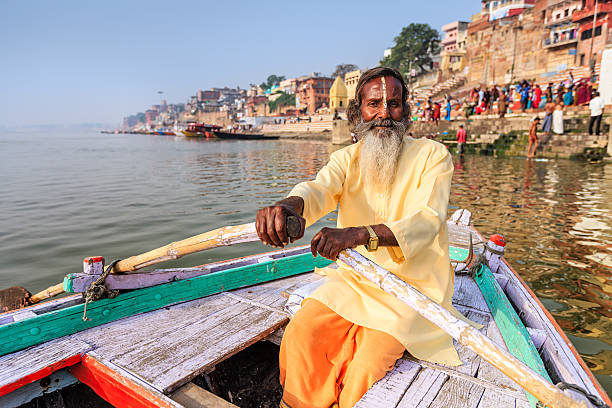 садху гребной лодке на священный река ганг в варанаси - varanasi indian culture nautical vessel ganges river стоковые фото и изображения