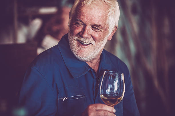 Senior Man with Beard Drinking Glass of White Wine Senior Man with Beard Drinking Glass of White Wine wine producer stock pictures, royalty-free photos & images