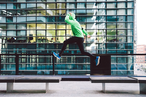 Mature man running and jumping during sport training outdoors, cityscape on background.