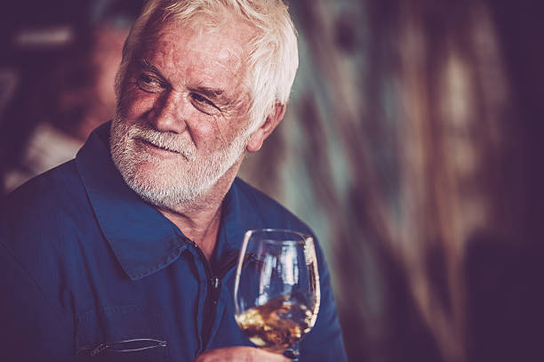 istock Senior Man with Beard Drinking Glass of White Wine 579774012