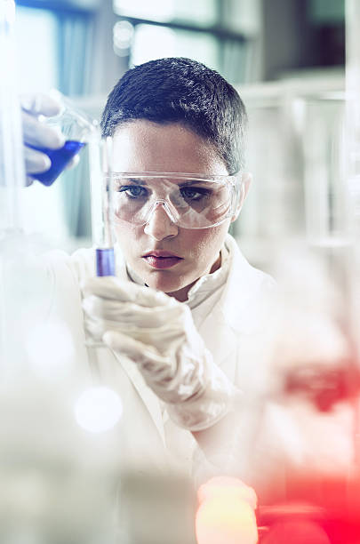istock Scientist pouring a reagent into a measuring cylinder 579776388