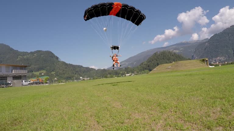 Tandem skydivers landing on field