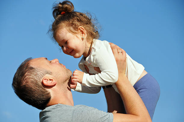 istock Father holds daughter on hands against the sky 580091982