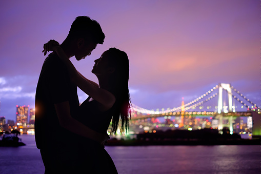 silhouette of romantic lovers with Odaiba in tokyo with sunset